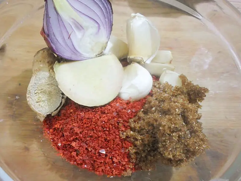 Now, for the kimchi paste, simply process the red chili flakes, garlic, onion, sugar, fish sauce, and ginger in a food processor or blender with a bit of water to make a paste.