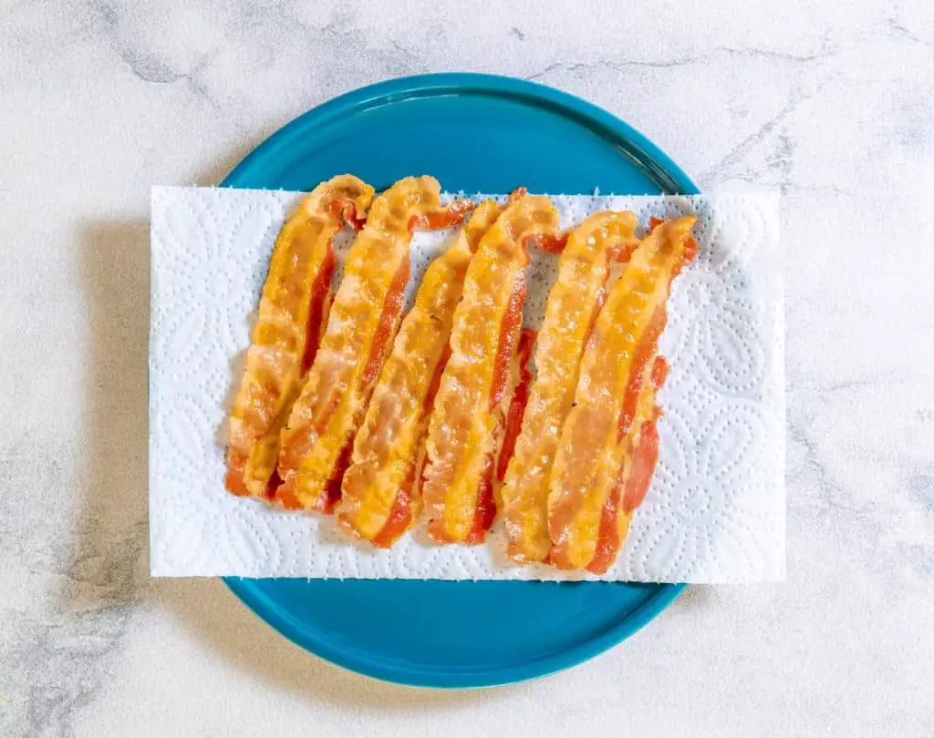 As bacon slices finish cooking, remove from heat and place on a paper towel lined plate to drain. Set aside to cool.