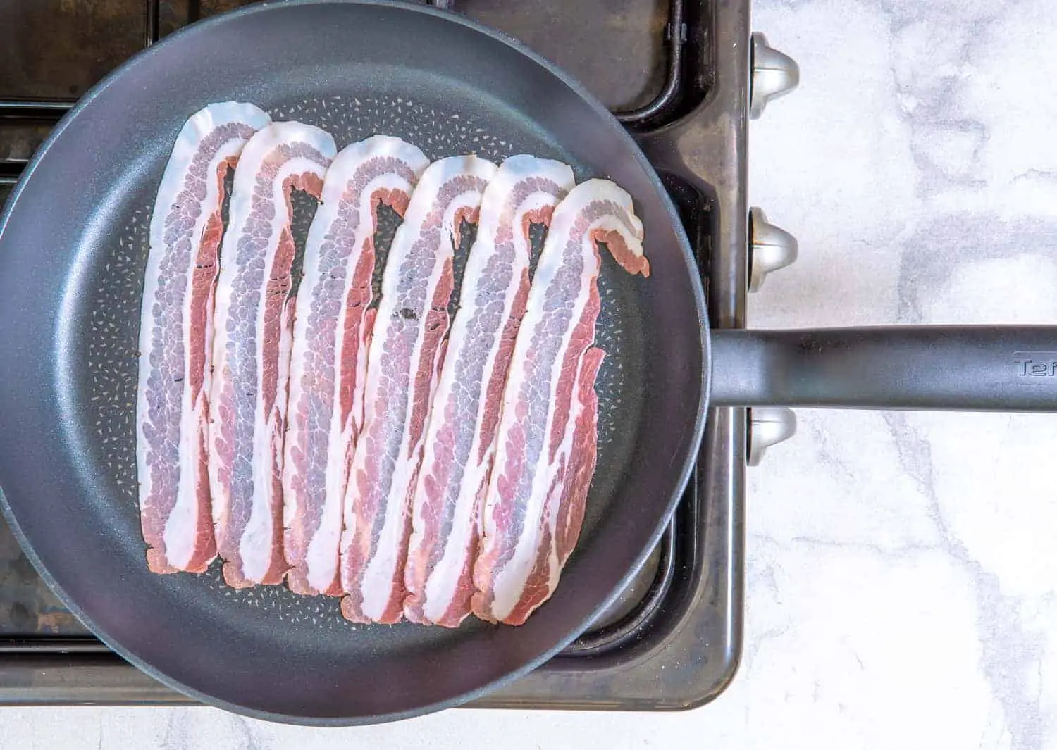 To cook the bacon, begin by placing the slices in a single layer on a cold, large skillet. 